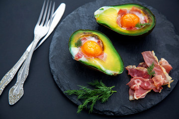 tasty baked avocado with an egg on a black background