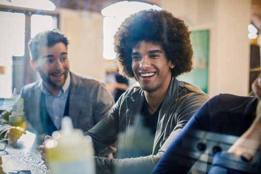Afro american Man and woman smiling to friend or colleagues and talking while waiting lunch at bar.Multiethnic people having break time in restaurant lounge.Corporate,diversity and social concepts.