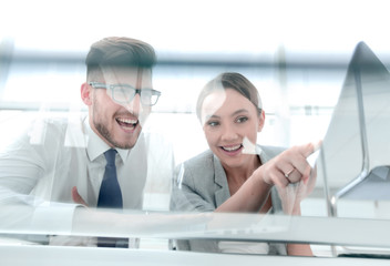 from the glass.smiling business couple sitting at the Desk