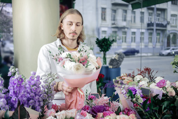 Attentive blonde male person selling his bouquets