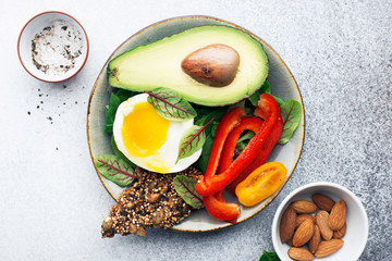 Keto bowl. Ketogenik diet snack. Cereal crackers without flour, paprika, avocado, eggs, spinach, nuts for a healthy diet. Top view