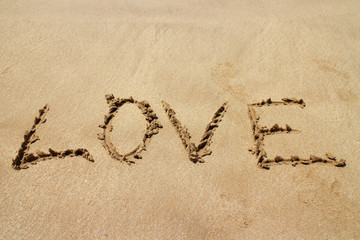 Happy Valentines day, LOVE lettering on the beach with wave and sunlight.