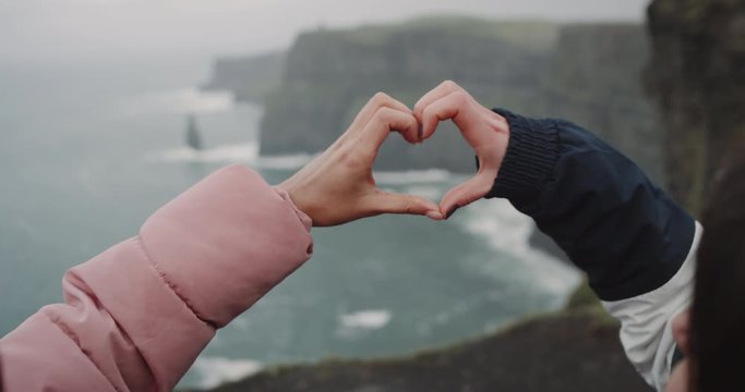Closeup details of a two frozen hands on the top of Cliffs of Moher make a big heart from hands. 4k