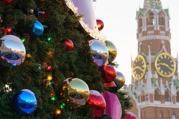 Multicolored toys on green Christmas tree branches on the background of the Moscow Kremlin