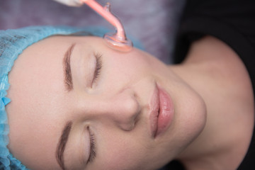 Receiving electric darsonval facial massage procedure at beauty salon