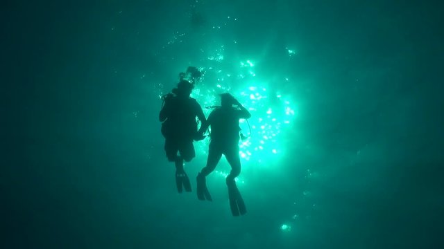 Divers silhouette against sun ball