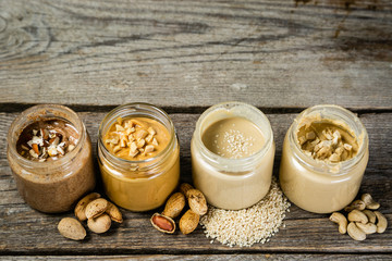 Obraz na płótnie Canvas Selection of nut butters - peanut, cashew, almond and sesame seeds, copy space
