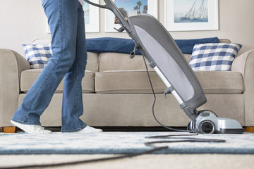 Low perspective photograph of a woman vacuuming her carpet at home
