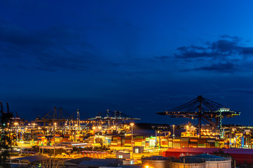 Fototapeta premium Container Cargo freight ship with working crane bridge in shipyard at dusk