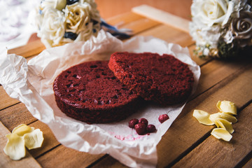 Red cake pies on a parchment and flowers on a wooden table