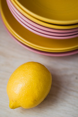 bright yellow lemon near a set of bright ware on a window sill