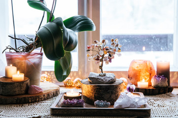 Feng Shui nature theme altar at home table and on window sill. Earth element( rock crystal clusters), wood element( wood discs), fire element( candles), rock salt candle holder. Positive home energy. - obrazy, fototapety, plakaty