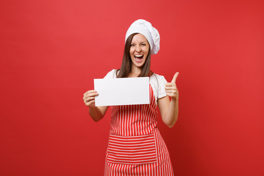 Housewife female chef cook or baker in striped apron white t-shirt toque chefs hat isolated on red wall background. Woman hold blank sign board, place for promotional text. Mock up copy space concept.