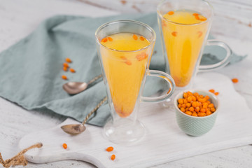 Two high glasses with colorful hot sea buckthorn tea with fresh sea buckthorn berries