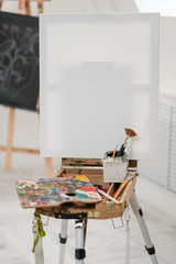 Artist's tools on the easel. Brushes, paints and canvas.
