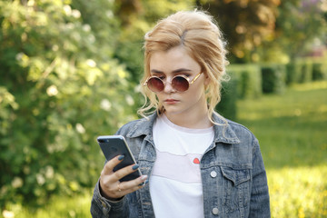 girl with round glasses. Hair in a bun. The girl with the phone. Girl looking at phone