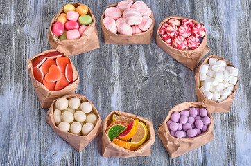 Colored candy in paper bags on wooden background