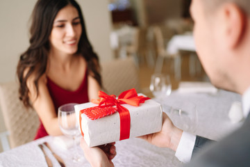 Valentine's Day concept. Happy couple in love with. A young loving couple celebrating Valentine's Day in the restaurant. Lovers give each other gifts. Romance restaurant for Valentine's Day- concept.