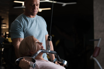 Strong male professional trainer helps his client