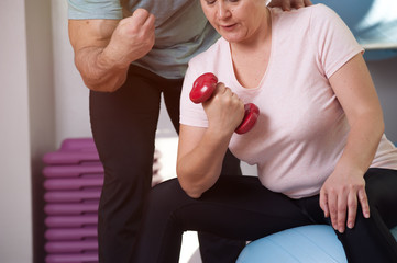 Woman with extra weight trains with dumbbells