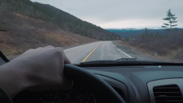 Driving POV on top of a mountains peak. The window view is larger mountains in the distance.