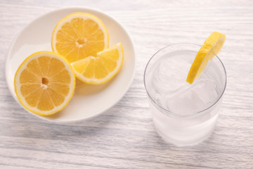 Refreshing cold water with lemon. With ice. Ready to eat. Next is a knife after cutting fruit. Misted glass.