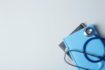Student textbooks, stethoscope and space for text on grey background. Medical education