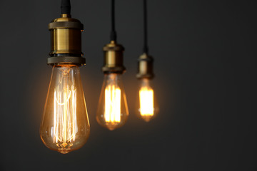 Pendant lamps with light bulbs on grey background. Space for text