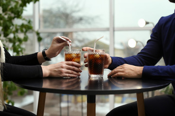 Couple with glasses of cold cola at table in cafe, closeup