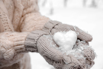 Fototapeta na wymiar Woman holding heart made of snow, closeup view