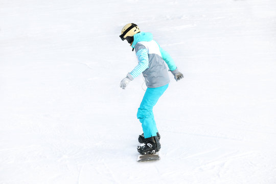 Woman in suit snowboarding on hill. Winter vacation