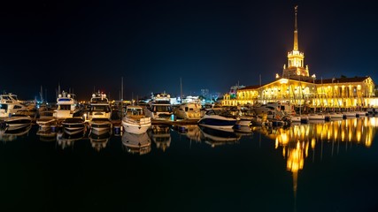 Fototapeta na wymiar Marine Station of Sochi, illuminated with lights at night with reflection in water