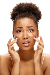 Young girl in shock of her acne. Photo of african american girl with problem skin on white background. Skin care concept
