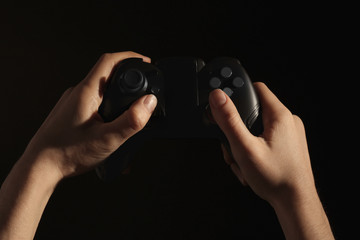Woman holding video game controller on black background, closeup