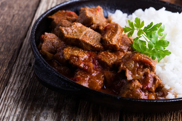 Beef stew served with white rice in cast iron skillet