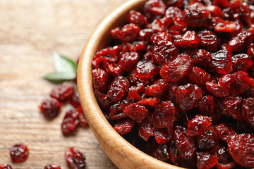 Bowl with cranberries on wooden table, closeup. Dried fruit as healthy snack