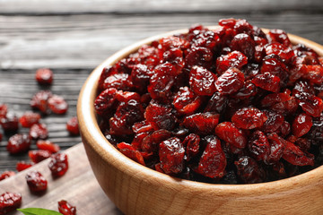 Bowl with cranberries on wooden table, closeup. Dried fruit as healthy snack