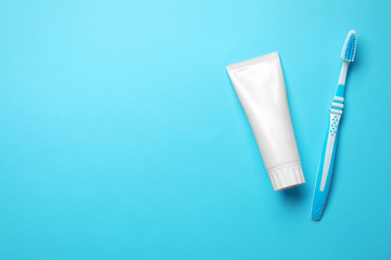 Blank tube of toothpaste and brush on color background, top view with space for text