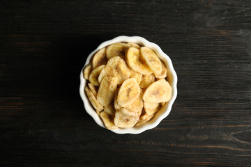 Bowl with sweet banana slices on wooden  table, top view. Dried fruit as healthy snack