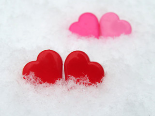 Fototapeta premium Valentine hearts in the snow, red and pink symbols of love. Background for romantic greeting card with free copy space
