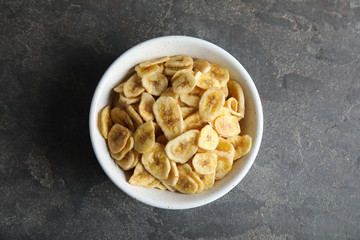 Bowl with sweet banana slices on grey background, top view. Dried fruit as healthy snack