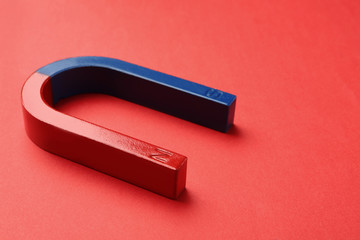 Red and blue horseshoe magnet on color background. Space for text