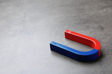 Red and blue horseshoe magnet on grey background. Space for text