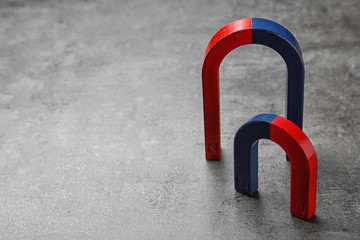 Red and blue horseshoe magnets on grey background. Space for text
