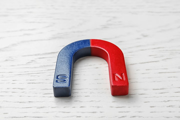 Red and blue horseshoe magnet on wooden background