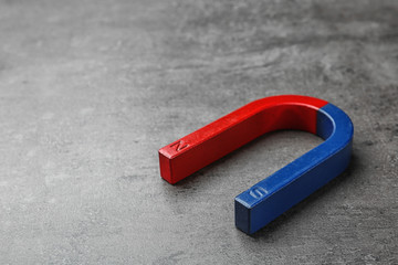 Red and blue horseshoe magnet on grey background. Space for text