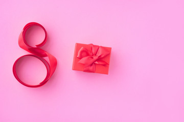 Women's Day greeting card, March 8. A gift in a red box on a pink background. selective focus