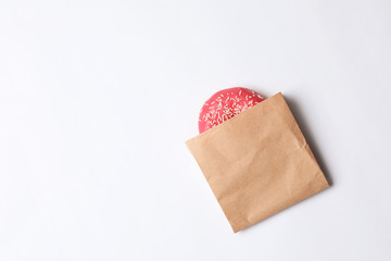 Paper bag with glazed doughnut on white background, top view. Space for text