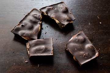Bitter Almond Chocolate Pieces on Dark Wooden Surface.
