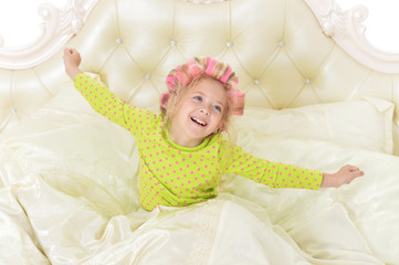 Lovely little girl with pink curlers having fun